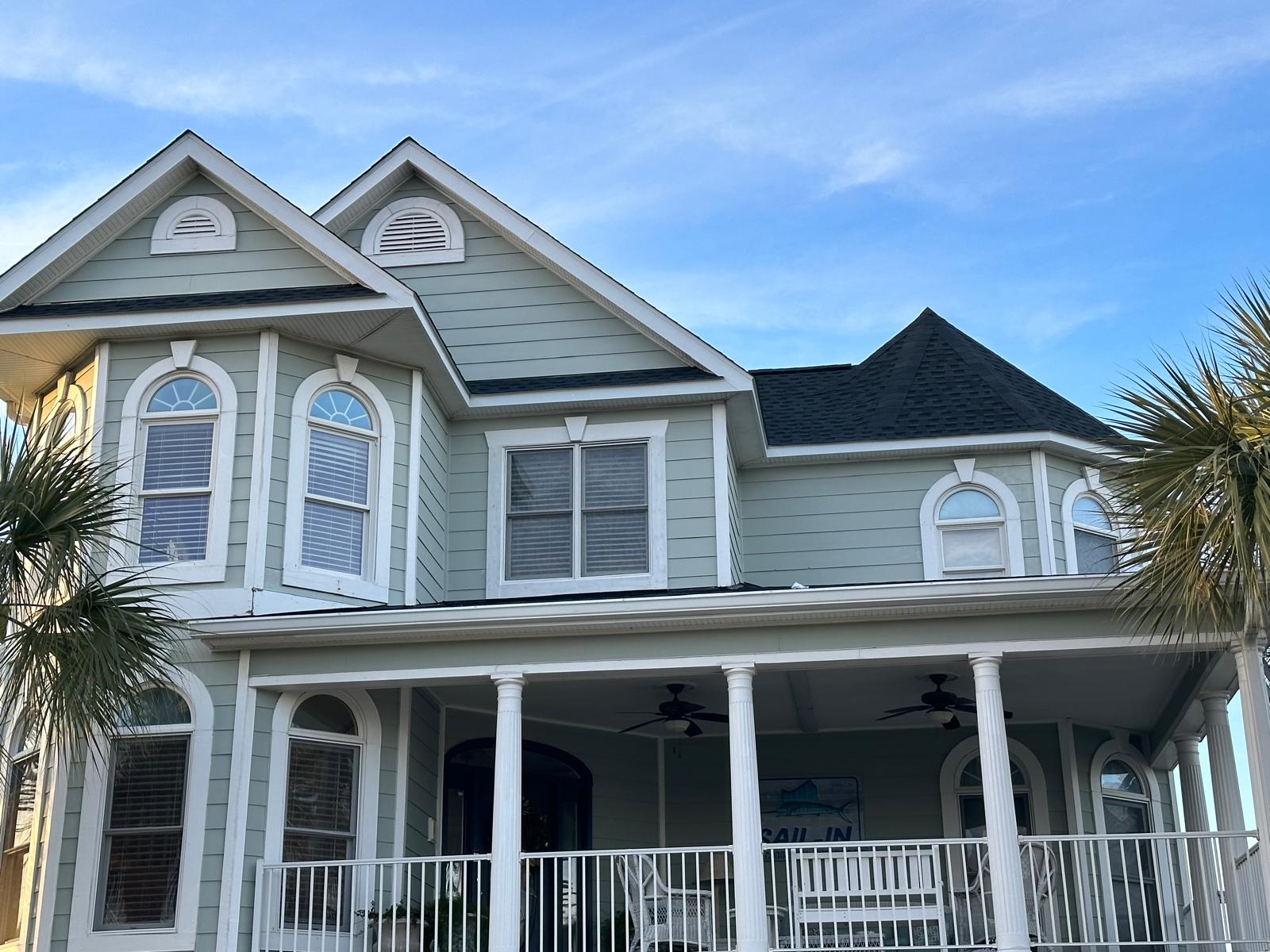Light blue coastal home with white trim and a wraparound porch, freshly painted by AP Painting & Cleaning